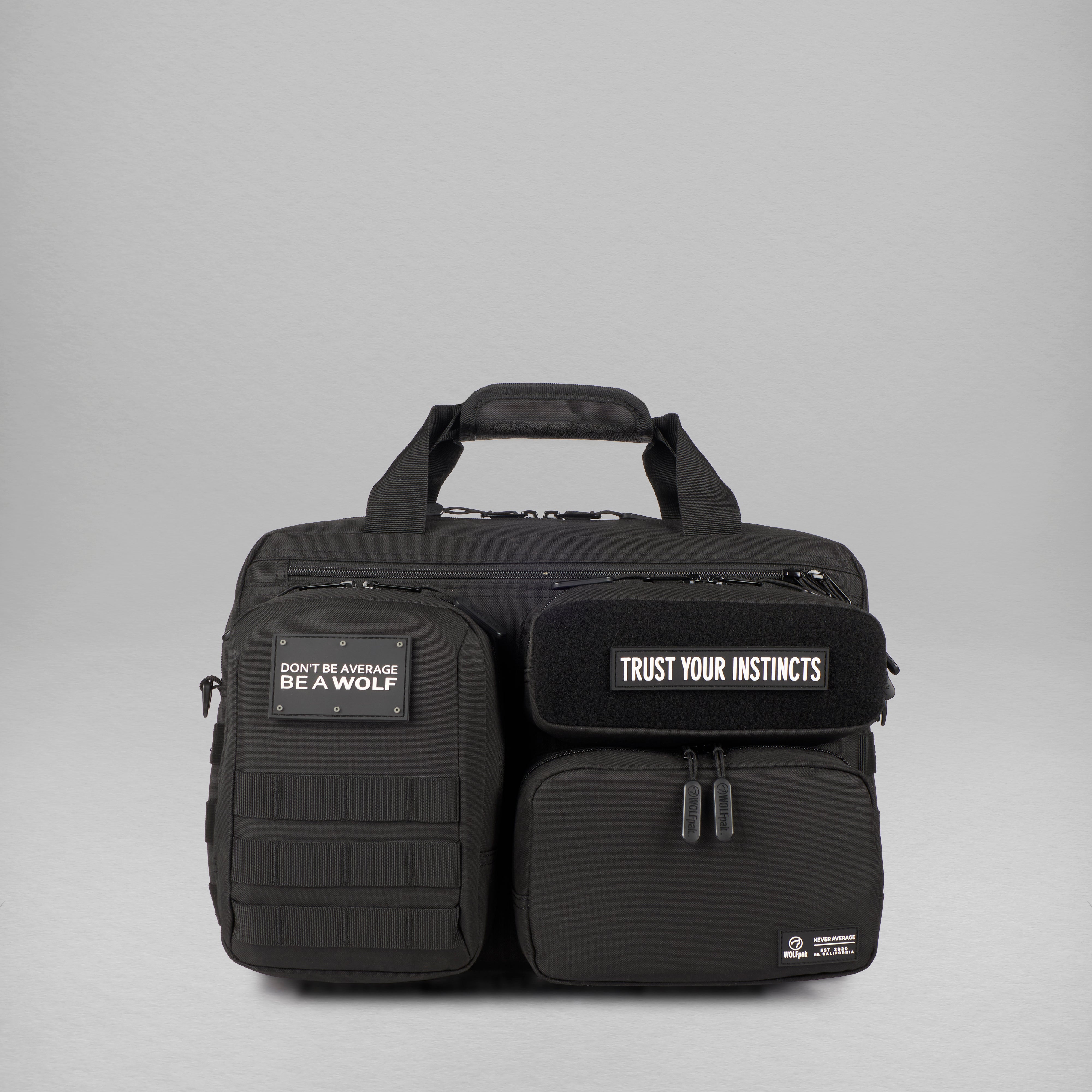 A black tactical briefcase with multiple zippered compartments, a top carry handle, and two black patches with white text reading 'DON'T BE AVERAGE BE A WOLF' and 'TRUST YOUR INSTINCTS', shown on a light gray studio background.