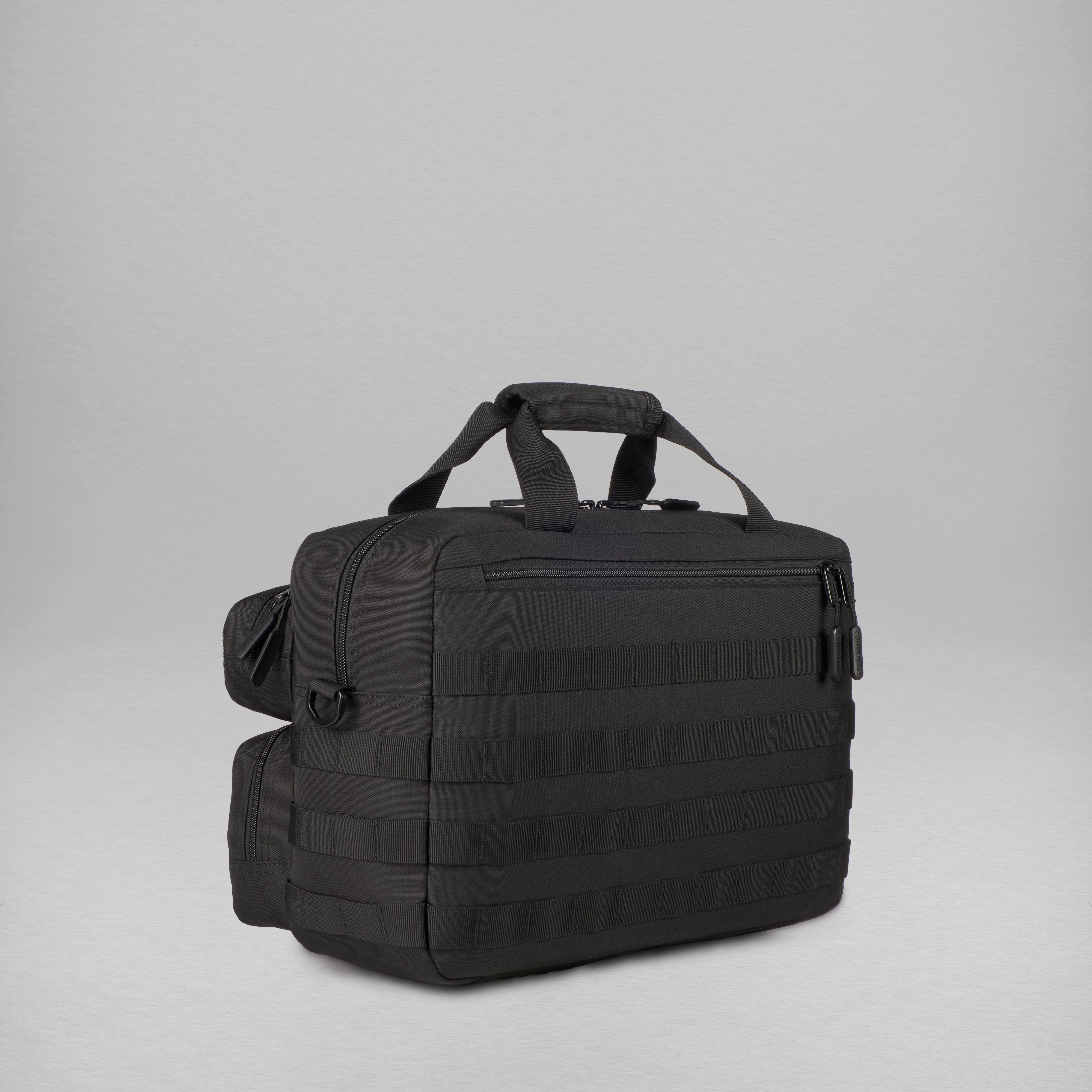 A black tactical-style briefcase with top carry handles, a zippered main compartment, and horizontal webbing straps on the front, photographed on a light gray studio background.