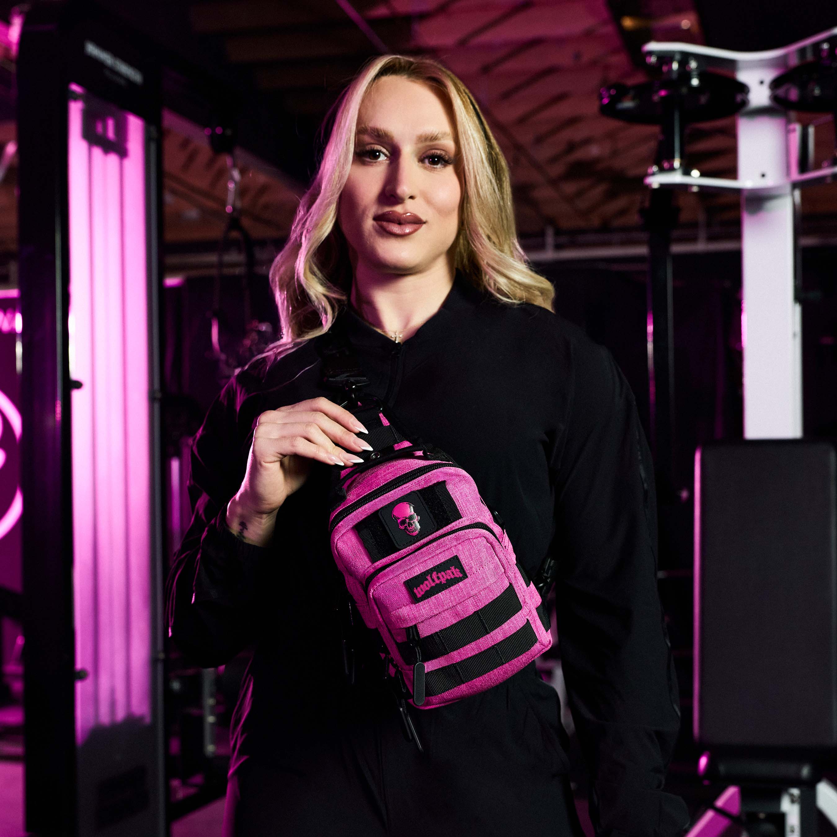 Woman holding a pink and black bag in a dark room with purple lighting