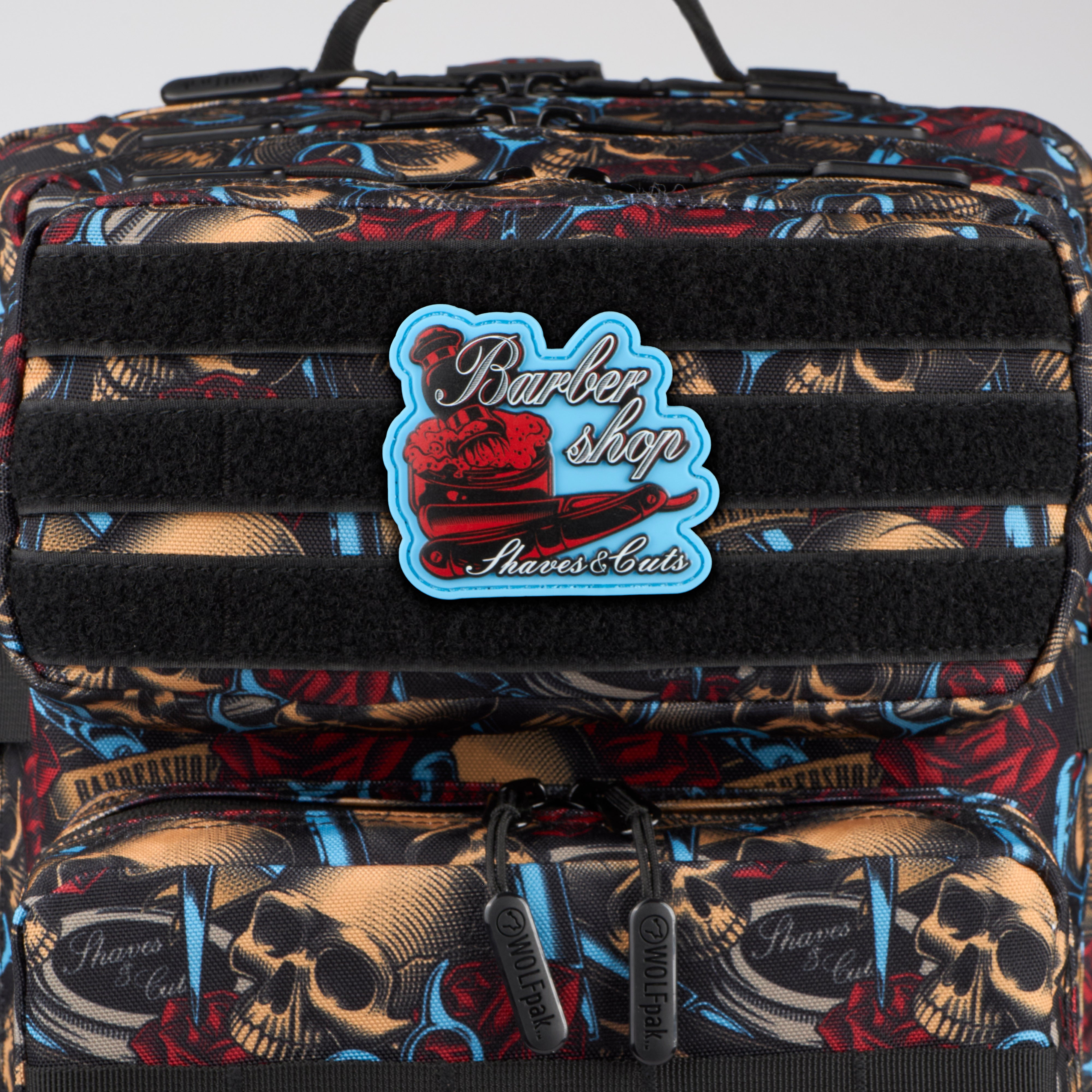 Multicolored patterned bag with 'Barber Shop Shaves & Cuts' logo on a white background