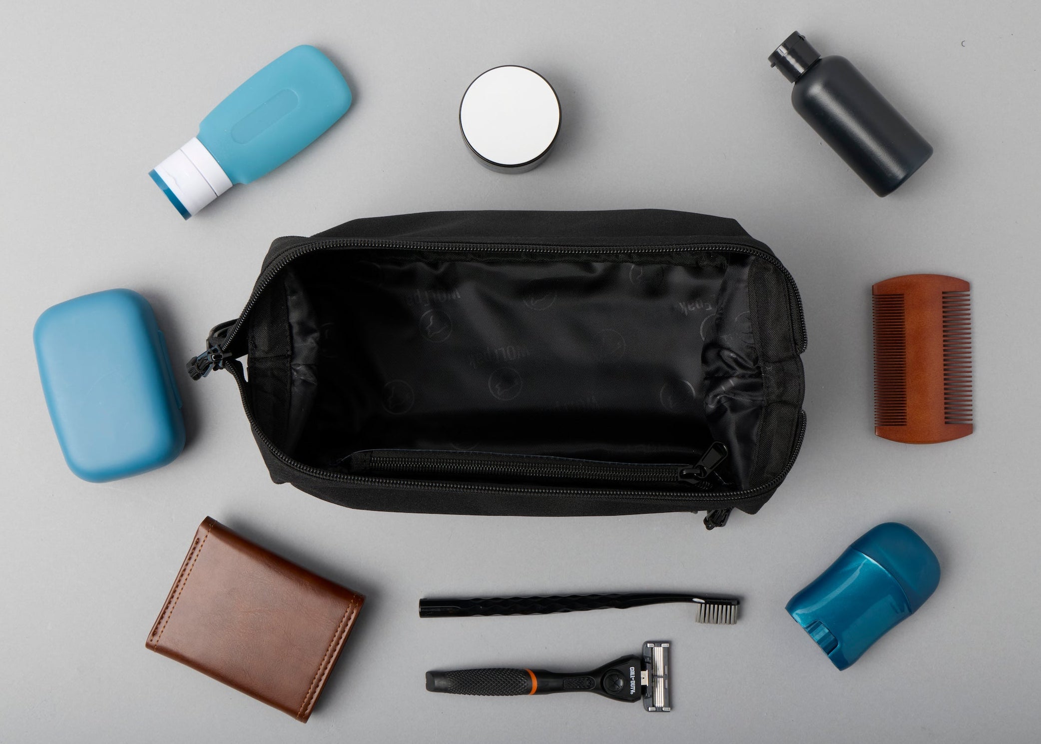 Collection of grooming items including a black toiletry bag on a gray background