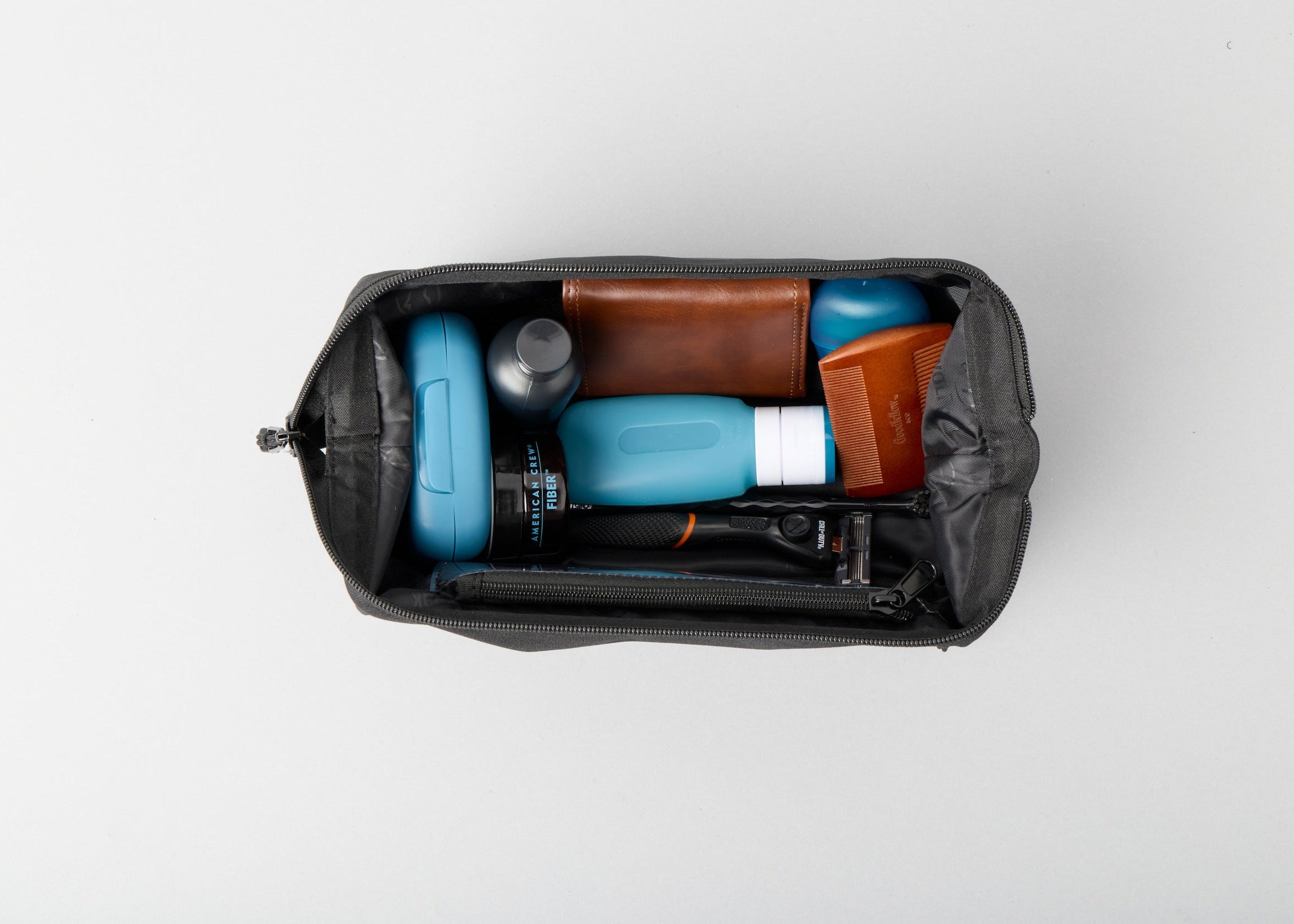 Black toiletry bag with travel items on a white background