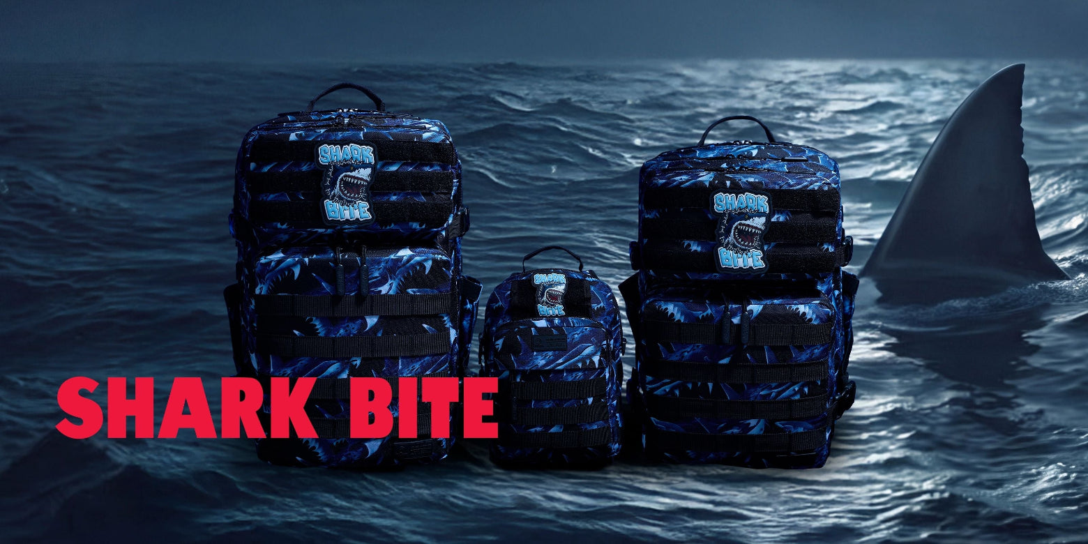 Three dark blue and black camouflage backpacks arranged on ocean water, with a shark fin visible in the background and large red text reading 'SHARK BITE' across the lower left.
